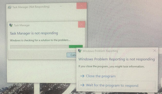 a picture taken of a screen showing a blank computer window titled: "Task Manager (Not Running)" on top is another window titled: "Task Manager" with a loading bar and the text "Task Manager is not responding." and yet another window on top titled "Windows